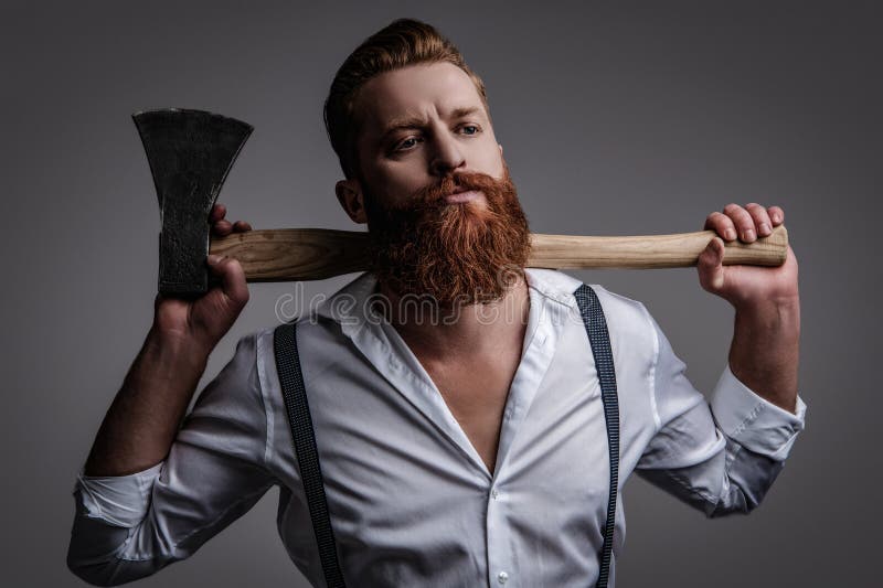 Uomo maschile. mascolinità dell'uomo barbuto con un'ascia isolata in grigio. uomo brutale caucasico con barba e baffi fotografie stock libere da diritti