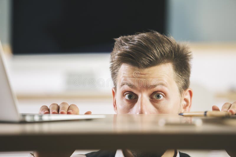 Uomo pazzo che si nasconde dietro la tavola fotografie stock Uomo pazzo che si nasconde dietro la tavola fotografie stock