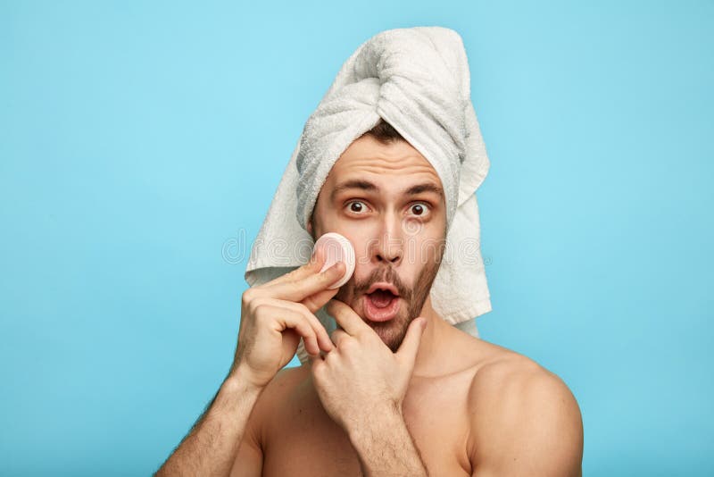 Uomo pazzo contentissimo che tiene un cuscinetto di cotone mentre preoccupandosi per la sua pelle immagine stock libera da diritti Uomo pazzo contentissimo che tiene un cuscinetto di cotone mentre preoccupandosi per la sua pelle immagine stock libera da diritti
