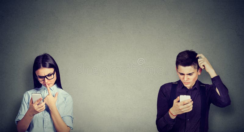 Uomo e donna perplessi che guardano un telefono cellulare immagini stock