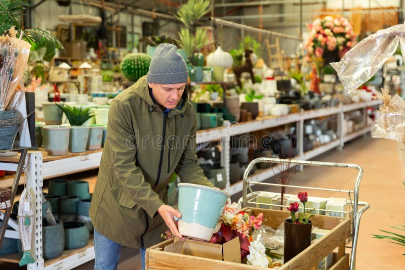 Uomo positivo che sceglie attentamente i vasi da fiore in un negozio di fiori immagine stock libera da diritti