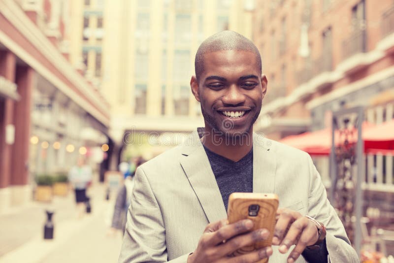 Uomo professionale urbano sorridente felice che per mezzo dello Smart Phone immagini stock libere da diritti Uomo professionale urbano sorridente felice che per mezzo dello Smart Phone immagini stock libere da diritti