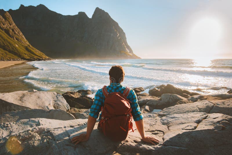 Uomo seduto sulla spiaggia di kvalvika che si gode la vista dell'oceano vacanze di viaggio eco turismo