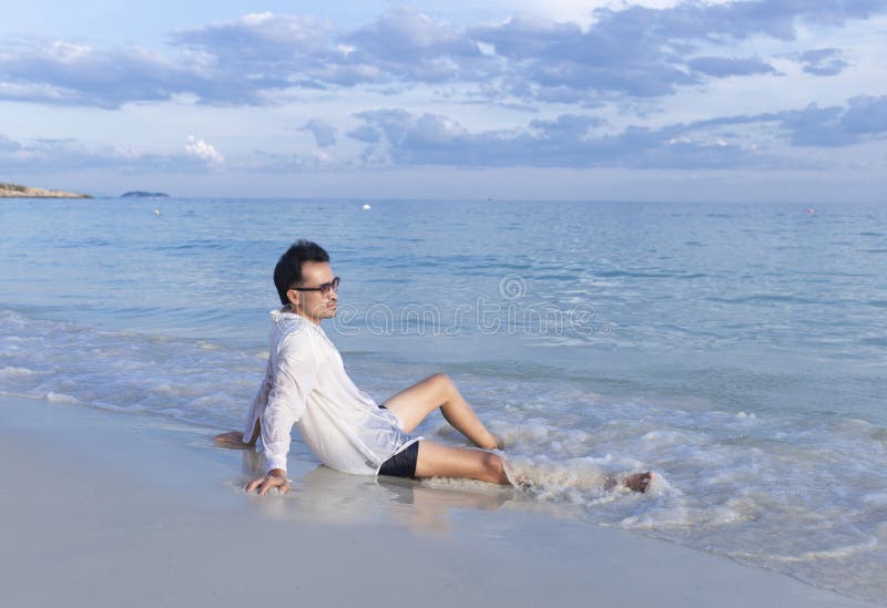 Uomo seduto sulla spiaggia di saikaew, koh ha chiamato rayong thailandia fotografia stock