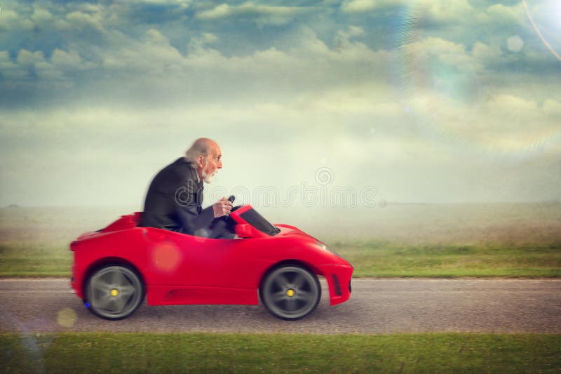 Senior man enjoying driving a toy racing car. Senior man enjoying driving a toy racing car