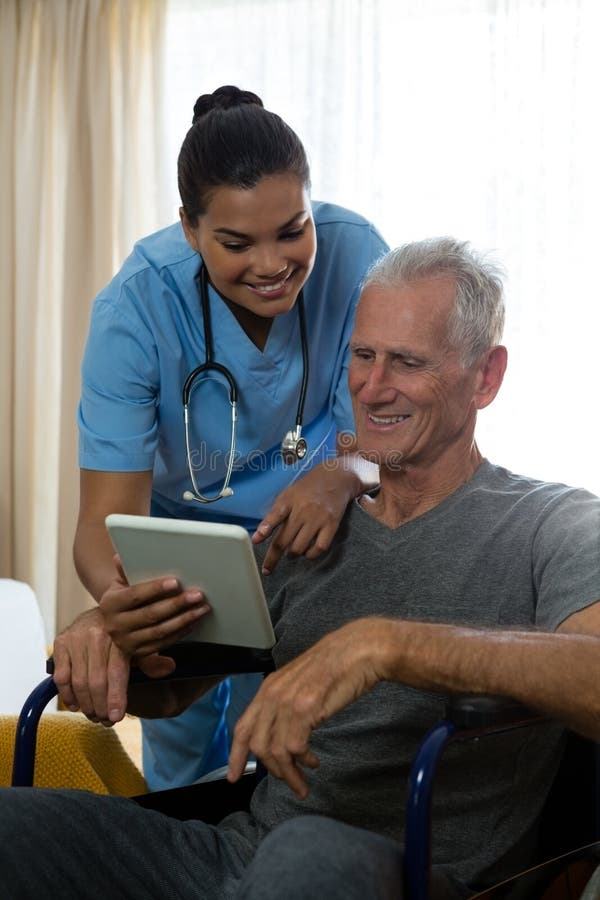 Uomo senior che mostra compressa digitale a medico nella casa di riposo fotografie stock libere da diritti Uomo senior che mostra compressa digitale a medico nella casa di riposo fotografie stock libere da diritti