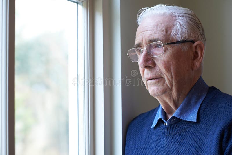 Uomo senior che soffre dalla depressione che guarda dai Wi fotografia stock Uomo senior che soffre dalla depressione che guarda dai Wi fotografia stock