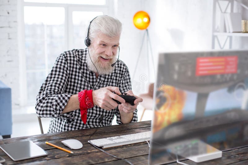 Uomo senior emozionante che gioca gioco online con il regolatore fotografia stock Uomo senior emozionante che gioca gioco online con il regolatore fotografia stock