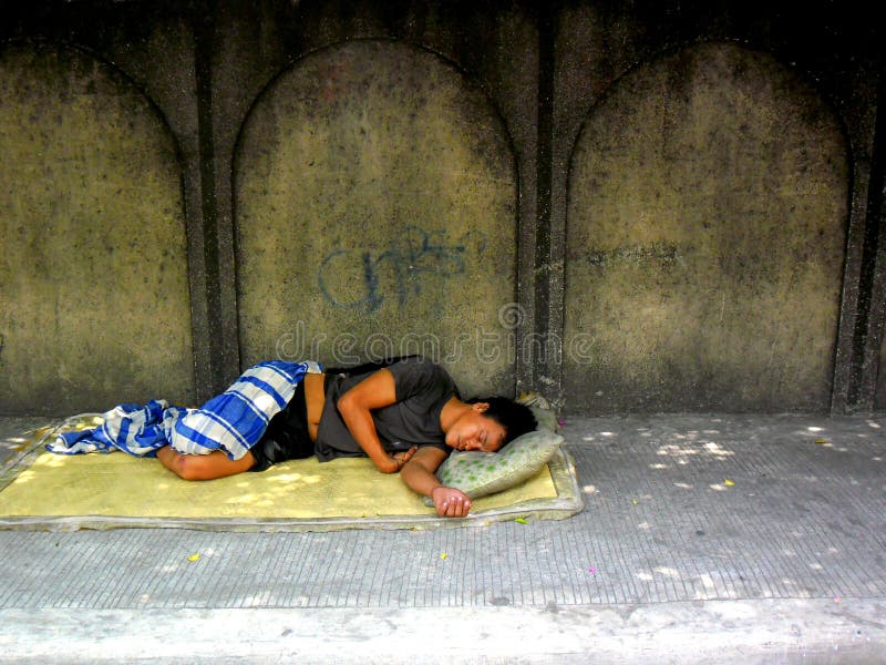 Uomo senza tetto che dorme su un marciapiede immagini stock Uomo senza tetto che dorme su un marciapiede immagini stock