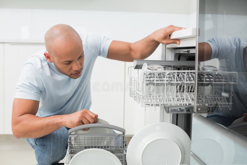 Uomo serio che utilizza lavastoviglie nella cucina
