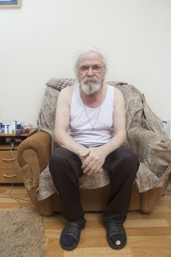 Uomo solo malato anziano nella poltrona a casa fotografie stock Uomo solo malato anziano nella poltrona a casa fotografie stock
