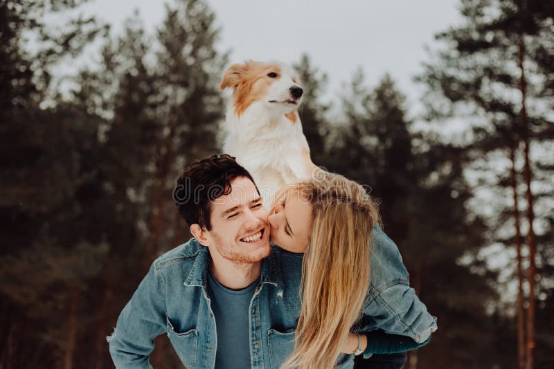 Uomo sorridente allegro felice con la ragazza ed il cane sul suo indietro baciare le coppie dei giovani nei vestiti del denim in fotografia stock libera da diritti Uomo sorridente allegro felice con la ragazza ed il cane sul suo indietro baciare le coppie dei giovani nei vestiti del denim in fotografia stock libera da diritti