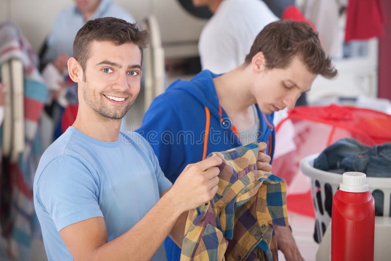 Uomo sorridente in lavanderia automatica fotografie stock libere da diritti Uomo sorridente in lavanderia automatica fotografie stock libere da diritti