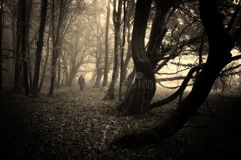 Uomo spaventoso che cammina in una foresta scura con nebbia