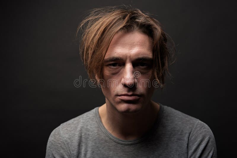 Portrait of exhausted sad guy with shaggy hair standing and looking at camera with apathy. Isolated on background. Portrait of exhausted sad guy with shaggy hair standing and looking at camera with apathy. Isolated on background