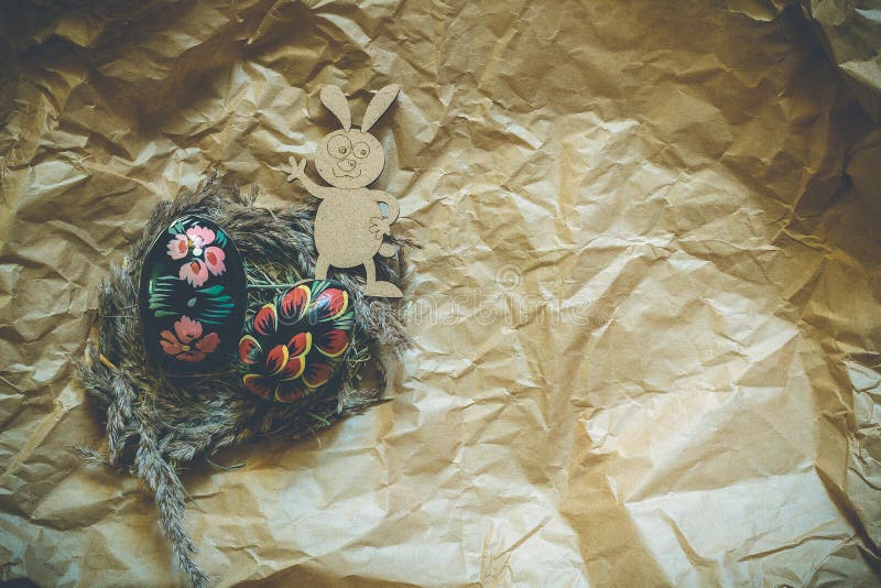 Uova di Pasqua di legno variopinte e coniglio di legno del fanny su un fondo della carta del mestiere modificato immagini stock Uova di Pasqua di legno variopinte e coniglio di legno del fanny su un fondo della carta del mestiere modificato immagini stock