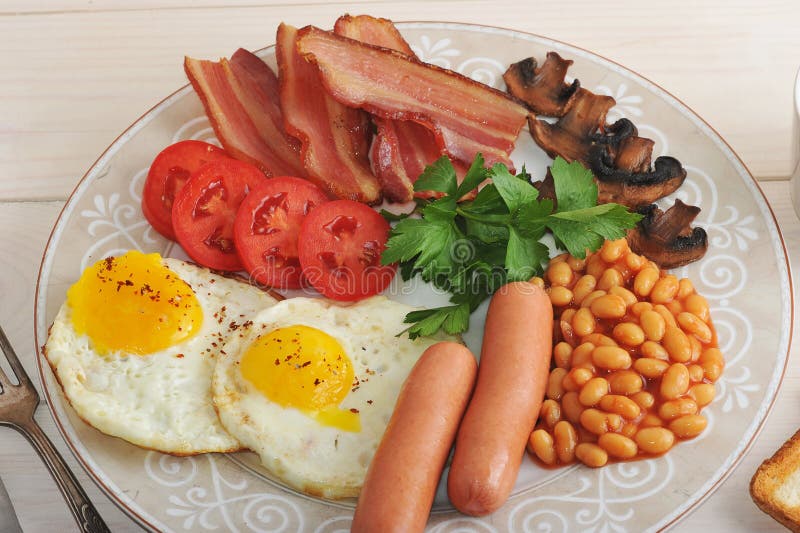 Uova fritte con bacon, i pomodori, i fagioli, i funghi e le salsiccie fotografia stock libera da diritti Uova fritte con bacon, i pomodori, i fagioli, i funghi e le salsiccie fotografia stock libera da diritti
