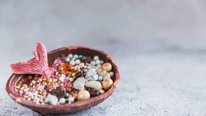 Uovo di cioccolato mezzo riempito di riso schioccato L'uovo è decorato con le pietre preziose e una coda delle sirene fotografie stock Uovo di cioccolato mezzo riempito di riso schioccato L'uovo è decorato con le pietre preziose e una coda delle sirene fotografie stock