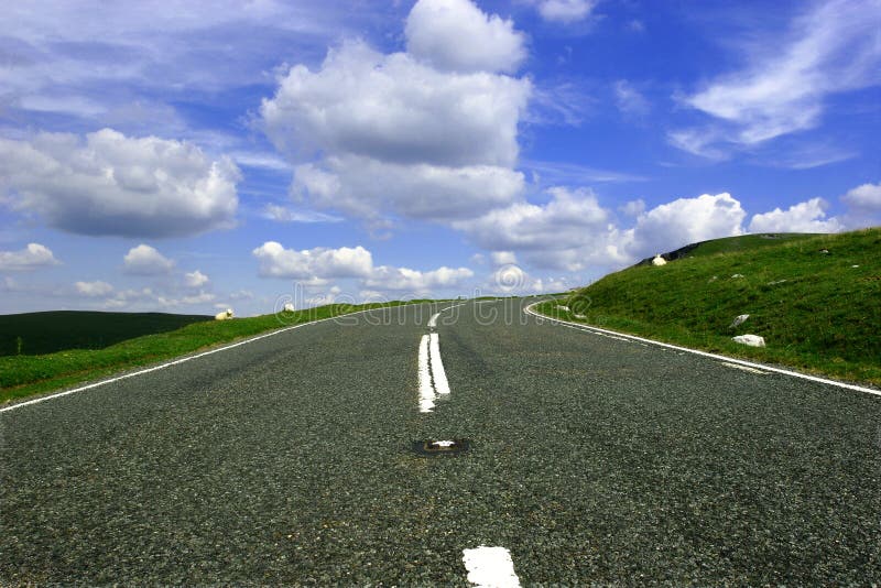 Montana carreteras bajo ángulo la ley mano doblar en distancia, colocar contra cielo azul hinchado blanco nubes.