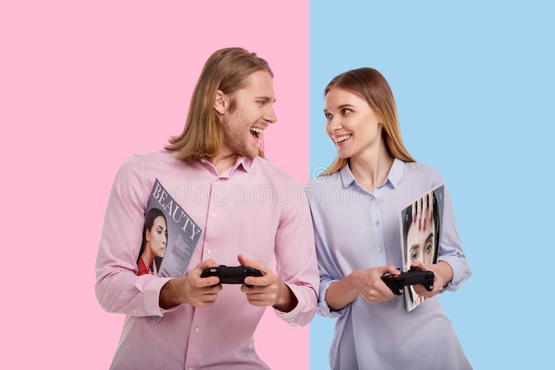 Competitive spirit. Joyful young women and her boyfriend looking at each other and smiling while playing a video game with controllers. Competitive spirit. Joyful young women and her boyfriend looking at each other and smiling while playing a video game with controllers