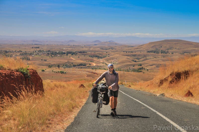 Človek tlačí na bicykli do kopca na strmé cesty v Strednej Madagaskar.