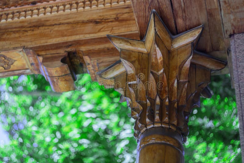 The upper rosette of a wooden pole with decorative wood carving patterns and decorative elements on the ceiling against the royalty free stock photos