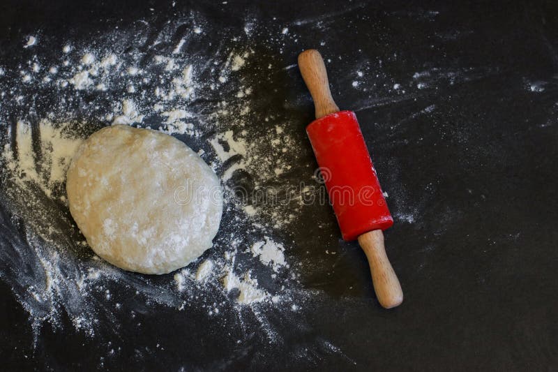 Upper view of a risen yeast dough for pizza or bread with red rolling pin stock photography