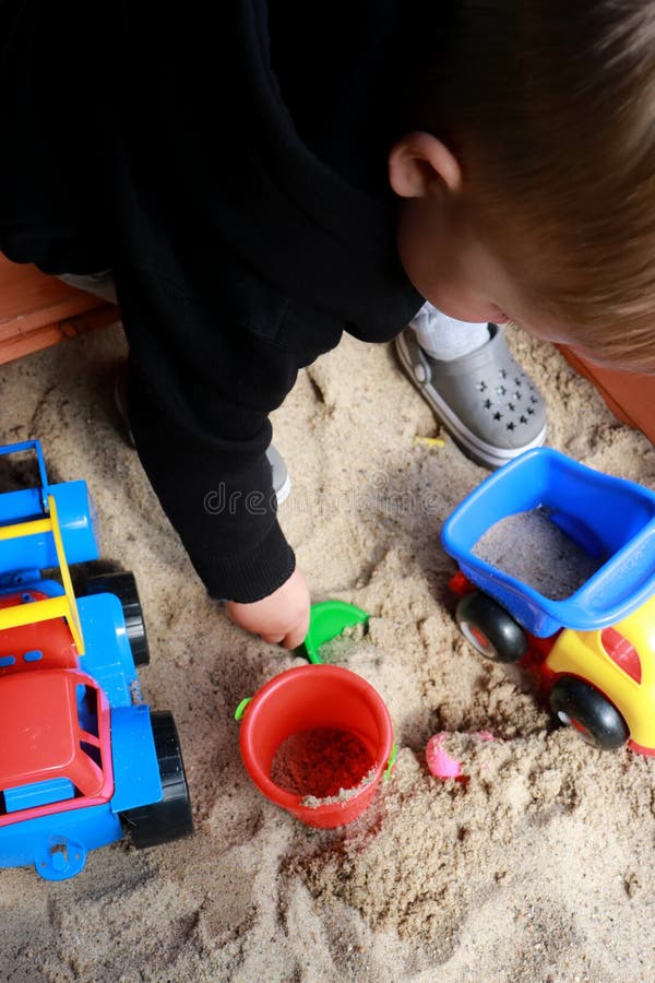 Toddler playing in the sand with toys stock image