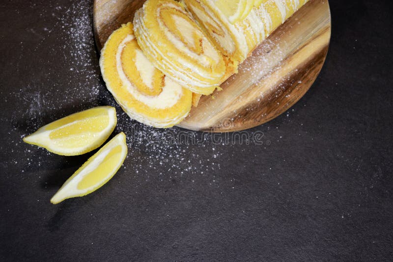 Upper view of a vanilla cake roll with lemon butter cream inside, dark grey marble table stock images