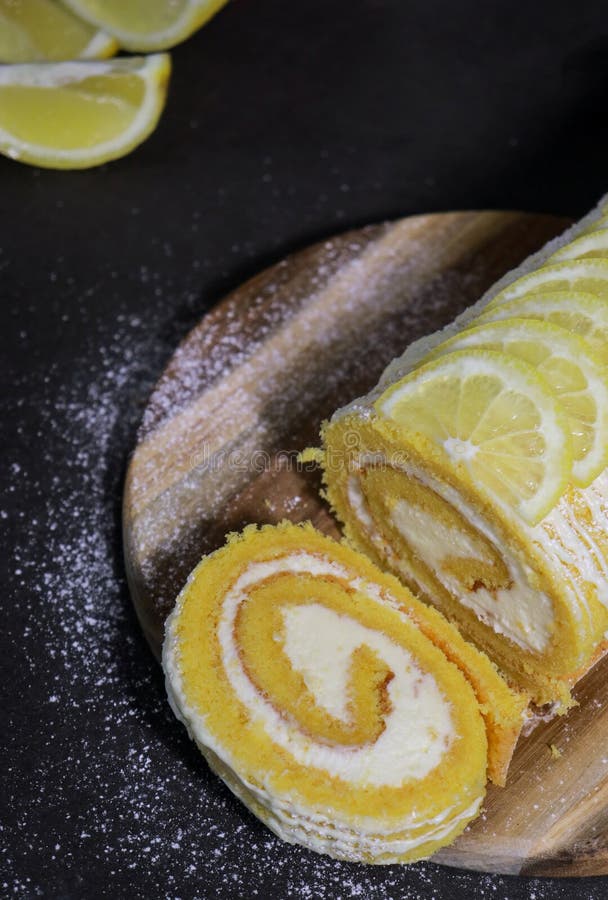 Upper view of a vanilla cake roll with lemon butter cream inside, dark grey marble table stock image