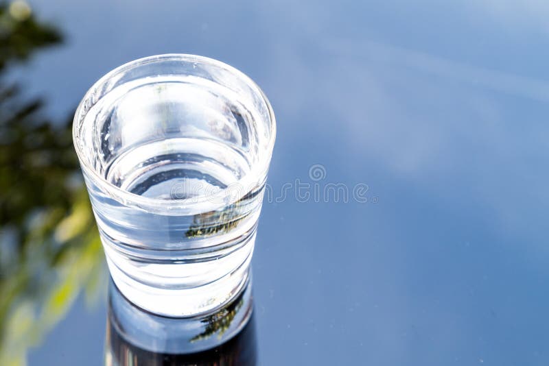 Uppfriskande vatten i genomskinligt exponeringsglas med reflexion mot bl arkivbilder Uppfriskande vatten i genomskinligt exponeringsglas med reflexion mot bl arkivbilder
