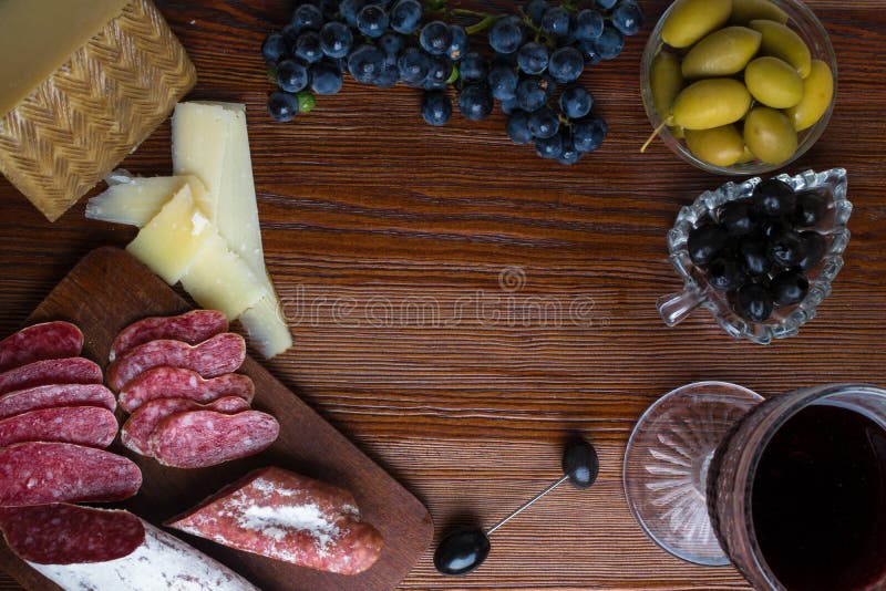 Uppläggningsfat med den skivade italienska hårdostpecorinotoscanoen, hemlagad torkad köttsalami, exponeringsglas av rött vin, dru royaltyfria bilder Uppläggningsfat med den skivade italienska hårdostpecorinotoscanoen, hemlagad torkad köttsalami, exponeringsglas av rött vin, dru royaltyfria bilder