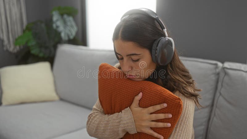 Uppmjukande inomhuslyssna på musik med hörlurar som kramar i lägenheten för rumshyllning och skapar en fredlig atmosfär arkivfoton