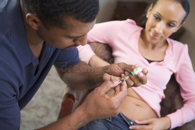 uppnå droger som att hjälpa injicerar manpregnanc till kvinnan royaltyfri bild uppnå droger som att hjälpa injicerar manpregnanc till kvinnan royaltyfri bild
