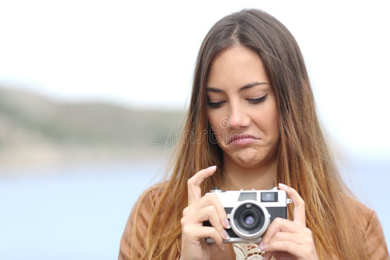 Uppriven kvinna som ser hennes gamla slrfotokamera arkivbild Uppriven kvinna som ser hennes gamla slrfotokamera arkivbild