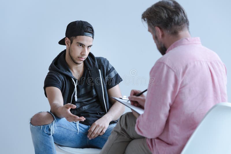 Upprorisk spansk man som talar till den yrkesmässiga psykologdurien arkivfoto Upprorisk spansk man som talar till den yrkesmässiga psykologdurien arkivfoto
