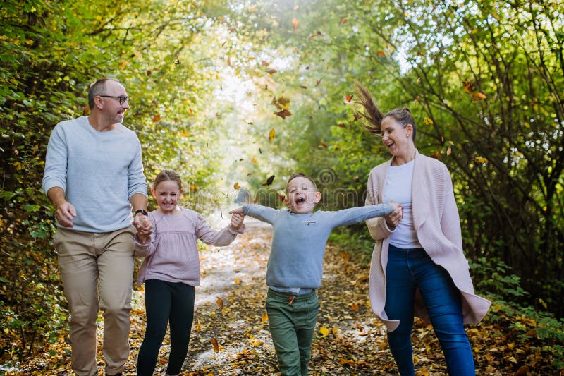 Uppspelad familj med barn som går i höstskogen. arkivfoton