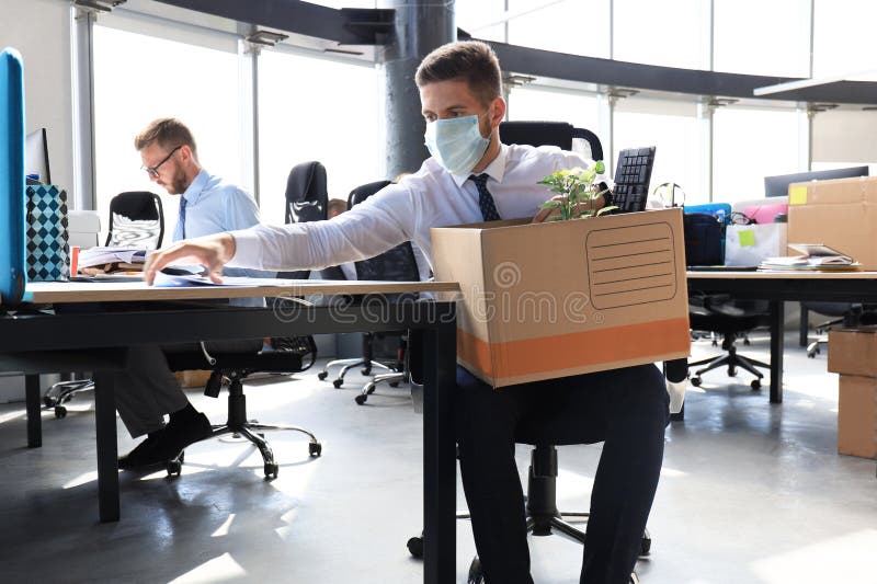 Dismissal employee in an epidemic coronavirus covid-19. Sad dismissed worker are taking his office supplies with him from office. Dismissal employee in an epidemic coronavirus covid-19. Sad dismissed worker are taking his office supplies with him from office.