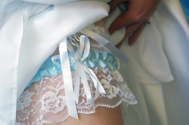 Close up of bride lifting dress up to show garter on leg. Close up of bride lifting dress up to show garter on leg.