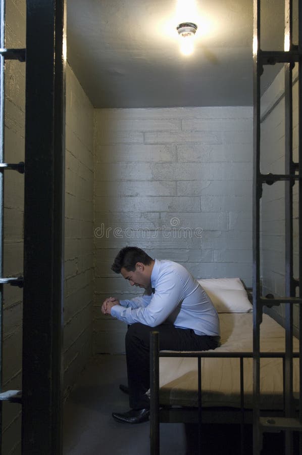 Upset Businessman Sitting On Bed In Prison stock image Upset Businessman Sitting On Bed In Prison stock image