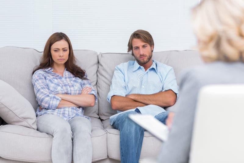 Upset couple sit on a sofa with arms crossed stock photography Upset couple sit on a sofa with arms crossed stock photography
