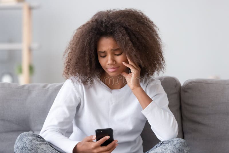 Upset depressed african teen girl looking at phone at home stock image Upset depressed african teen girl looking at phone at home stock image