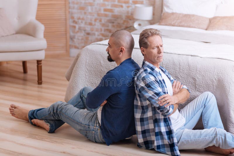 Upset gay couple sitting with crossed arms royalty free stock image
