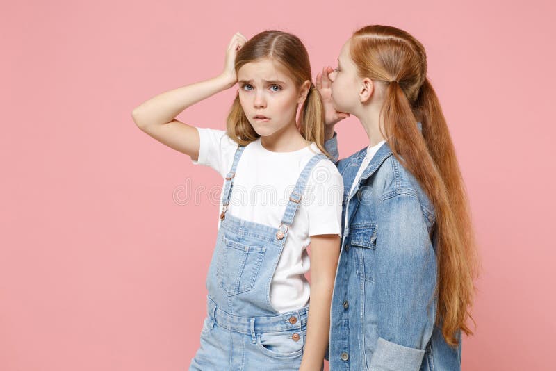 Upset little kids girls 12-13 years old in white t-shirt, denim clothes isolated on pastel pink background. Childhood