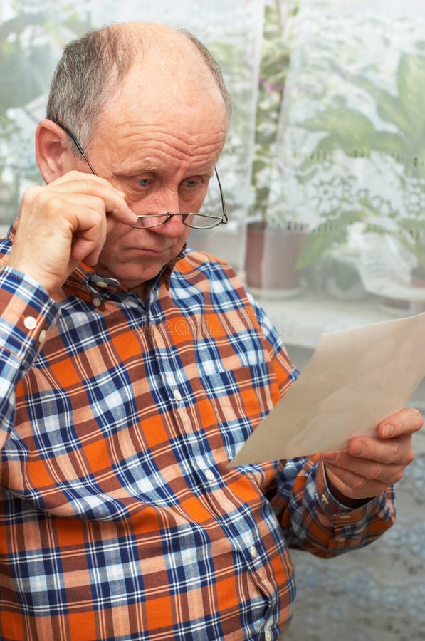 Upset senior man looks at photo stock photos Upset senior man looks at photo stock photos