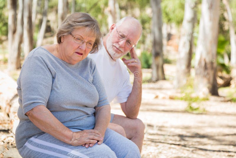 Upset Senior Woman Sits With Concerned Husband Outdoors stock images Upset Senior Woman Sits With Concerned Husband Outdoors stock images