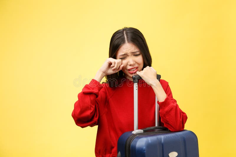 Upset tourist woman in summer casual clothes sit on suitcase put hands on head on yellow orange background