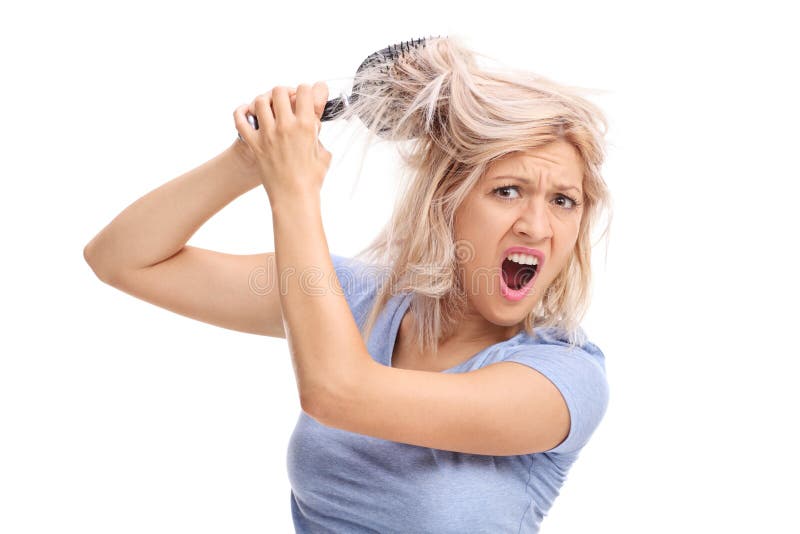 Studio shot of an upset woman with her hair tangled in a hairbrush isolated on white background