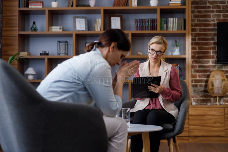 Upset Young Woman Has Counseling Session With Female Psychologist In