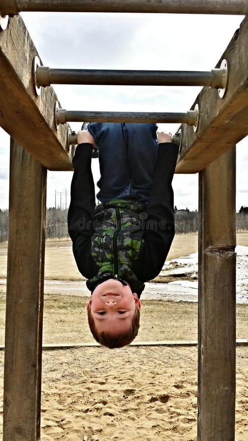 This little boy is having fun at the monkey bars, swinging and hanging upsi...